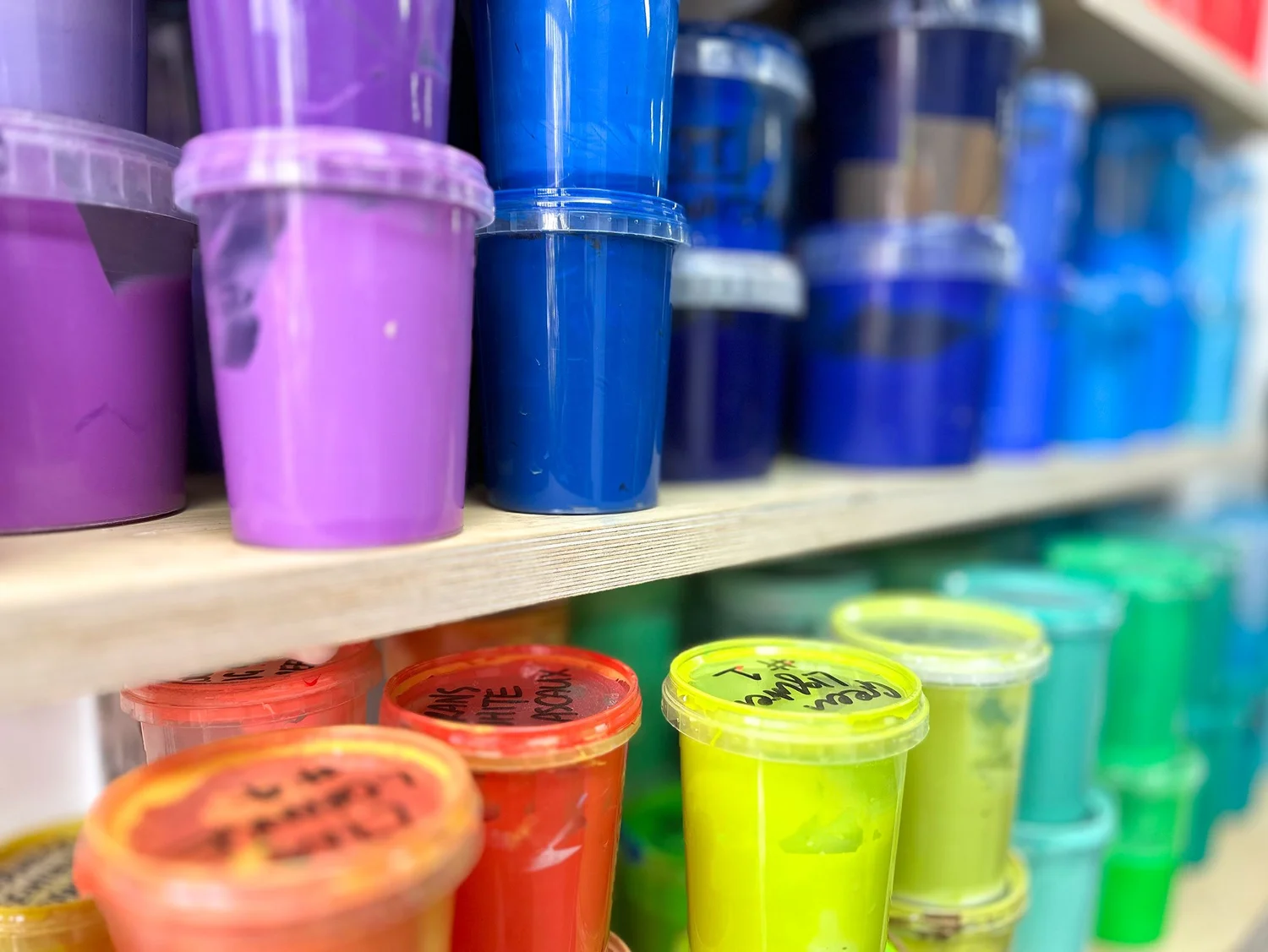 Pots of brightly coloured printing inks on studio shelves