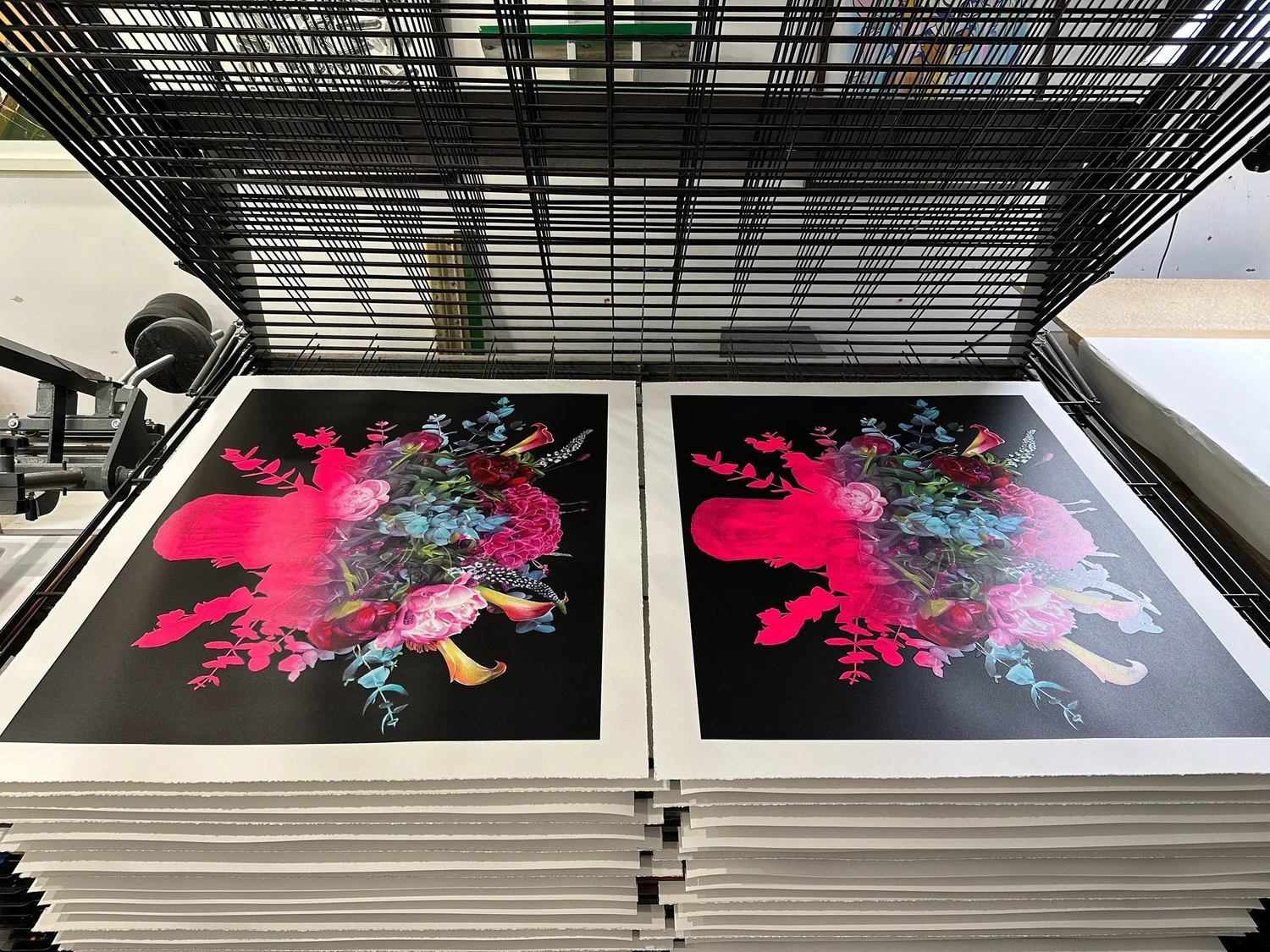 Two floral art prints drying on a studio rack