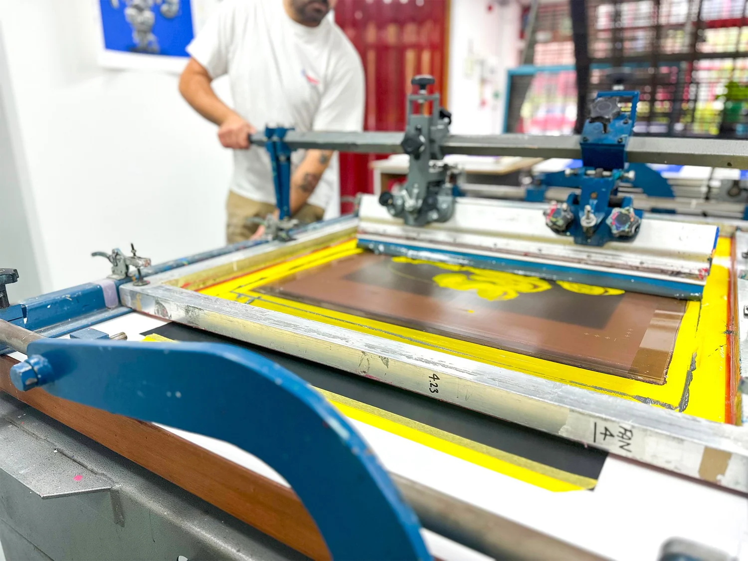 A printer working at the silkscreen press in the Bicep Press studio